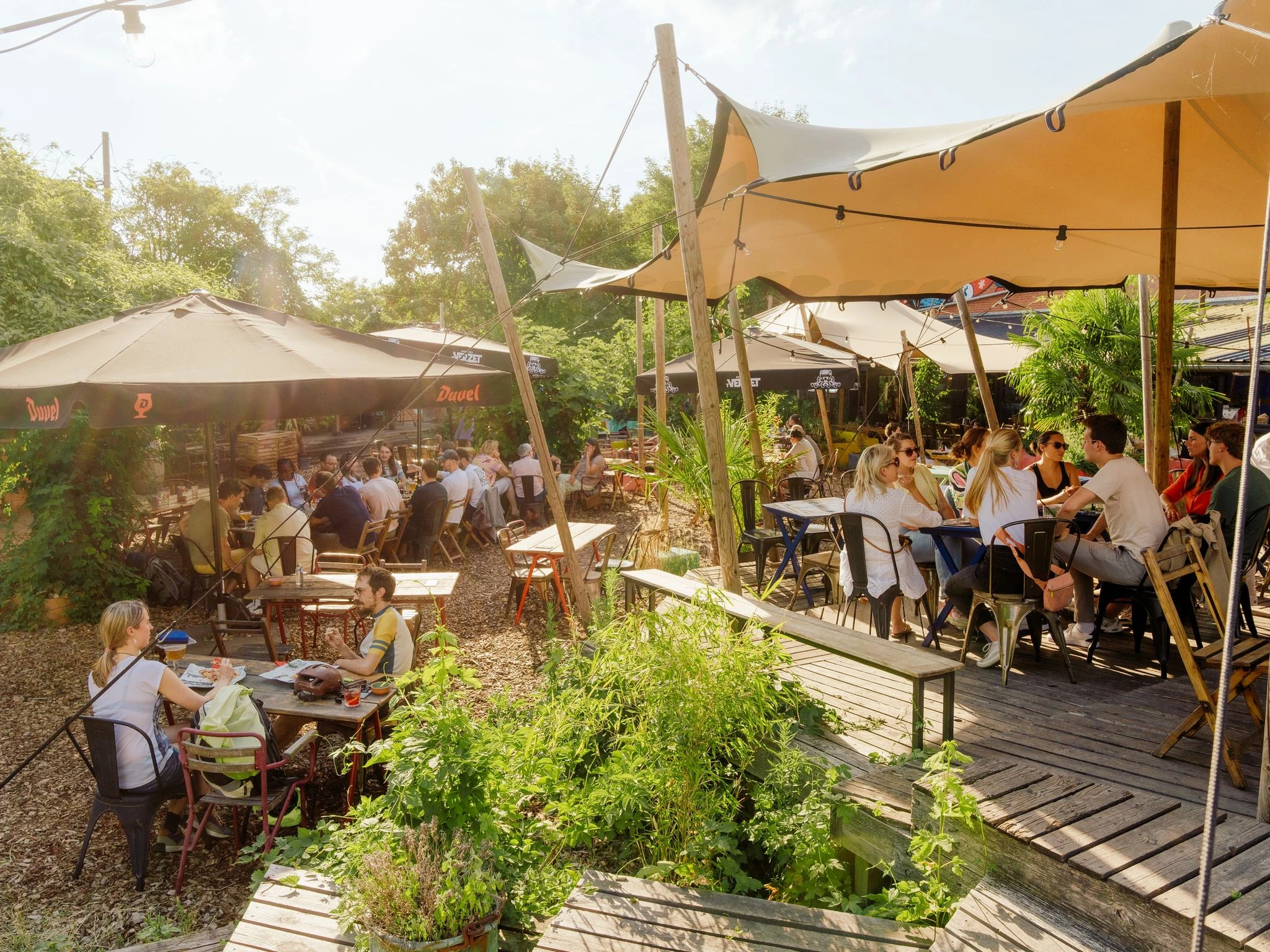 The Bar Bricolage summer garden at golden hour, with DIY wooden structures, benches and string lights